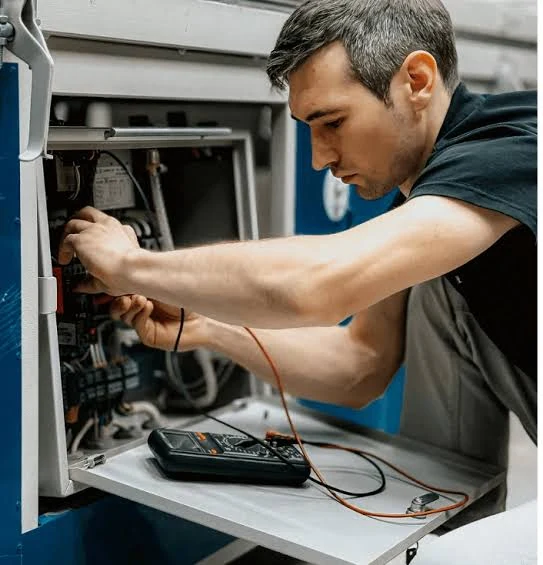 Technician testing electrical components inside HVAC equipment
